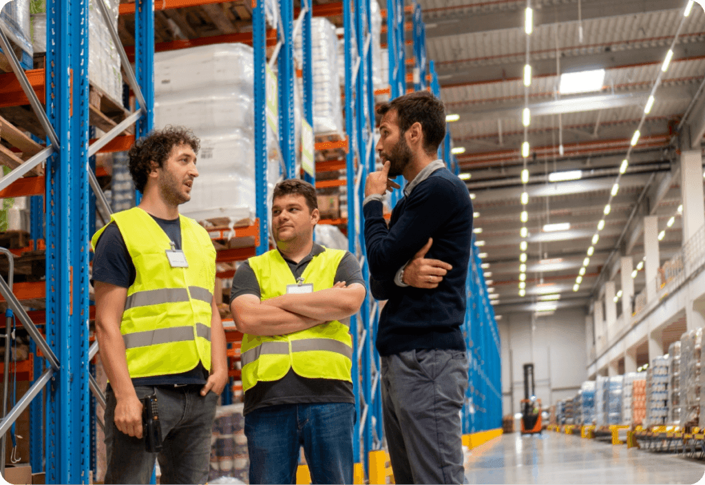 Three men in a warehouse discussing different ways to improve their warehousing management