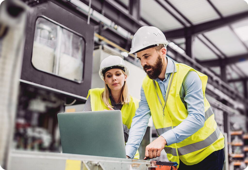 Two employees performing business inventory management in a warehouse with a laptop