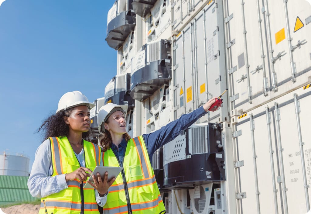 Two employees discuss supply chain visibility while overseeing cargo to lower operational expenses