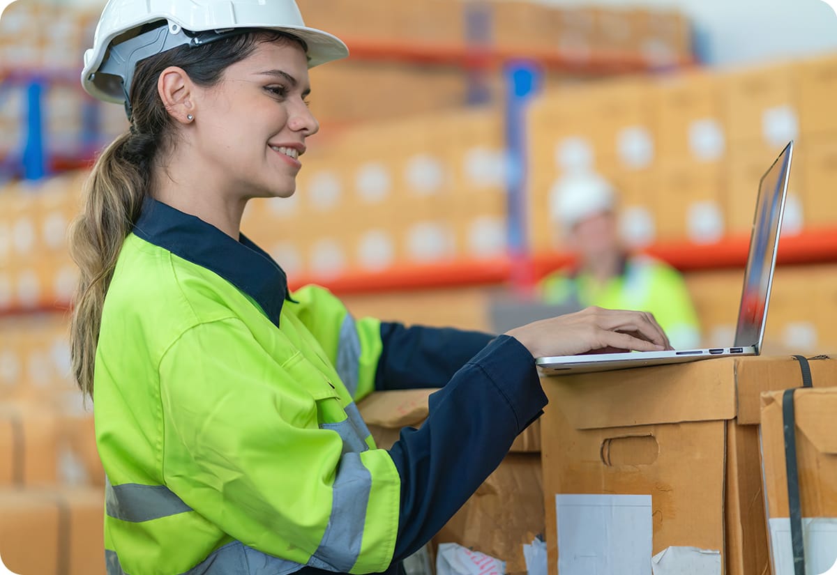 Warehouse employee checking data in a laptop as part of maintaining logistics visibility