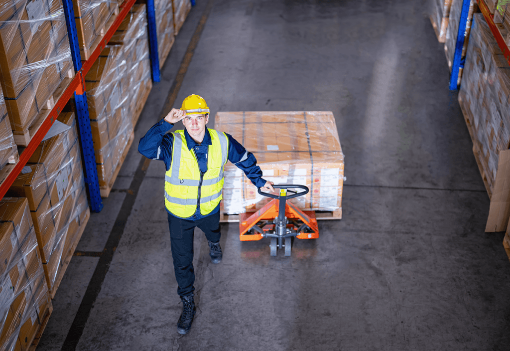 Employee pulling a cart with boxes in a warehouse, representing product warehousing operations and logistics handling