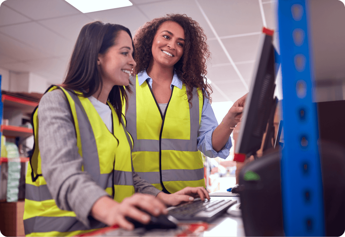 Two female employees reviewing freight invoice on computer monitor while one types on keyboard
