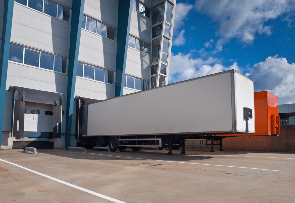 Freight truck at a warehouse loading dock for logistics transportation.